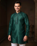 Man wearing a green kurta with white pants against a dark background