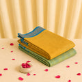 Yellow & Green Kanchi cotton saree with blue woven border folded and stacked display view.