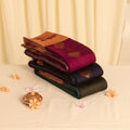 Elampillai silk cotton saree featuring floral buttas and metallic zari pallu stacked folded display angled view