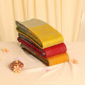Elampillai silk cotton sarees in yellow, red and green with silver check patterns, folded stack close up view.