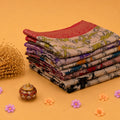 Collection of folded semi Chanderi sarees with vibrant multicolor prints on beige fabric front angled view