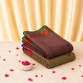 Kanchi cotton saree with brown body contrast red and green zari border neatly folded in stacked top view