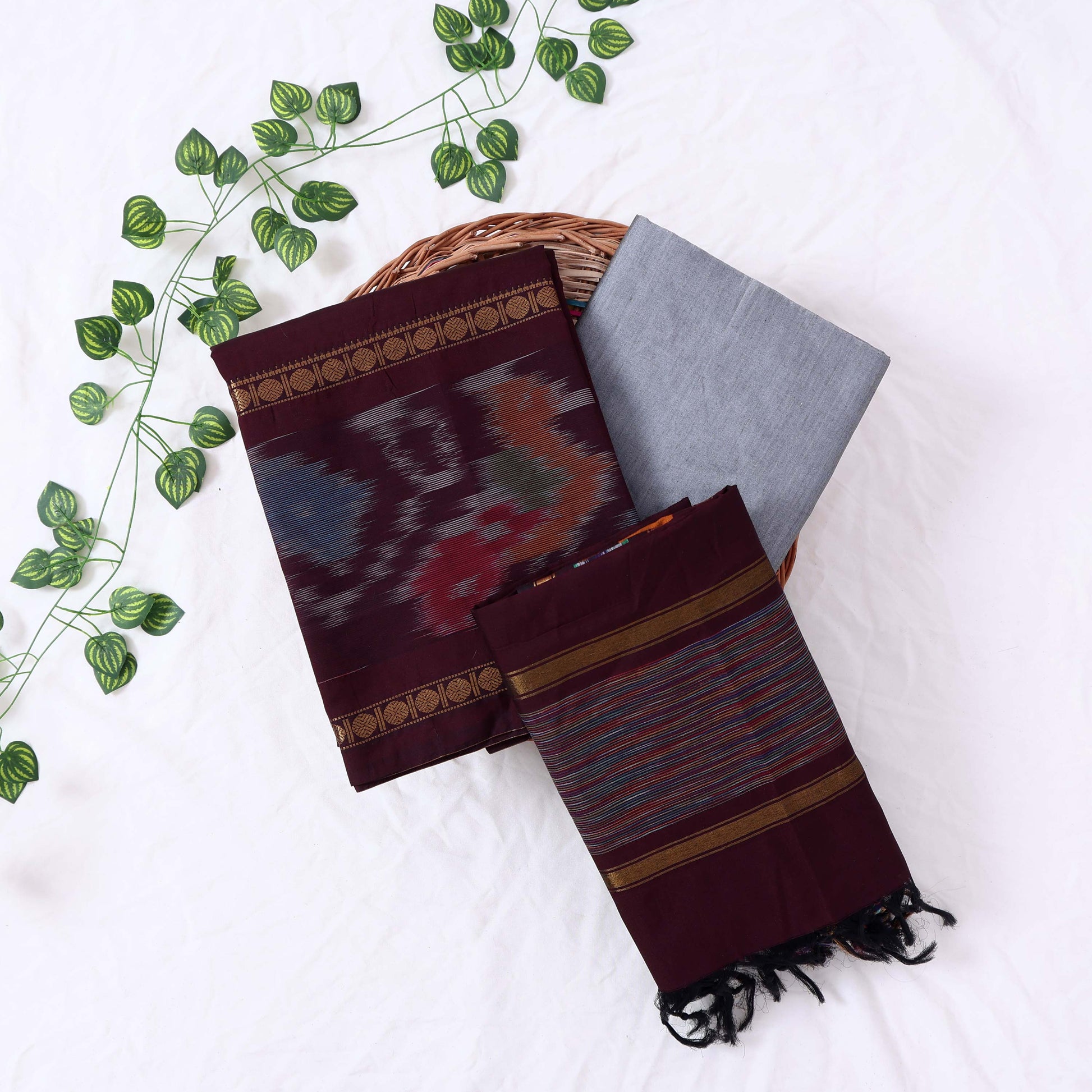 Top View Of Dark Maroon And Grey Salwar Suit Material With Striped Dupatta, Ikkat Woven Border, Tassel Details & Fabric Piece
