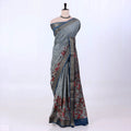 A grey and blue saree with red floral patterns and a metallic gold border.