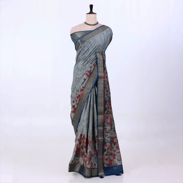 A grey and blue saree with red floral patterns and a metallic gold border.