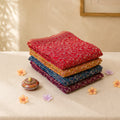 Art silk saree collection with floral vine prints in assorted colors folded stack display on tabletop
