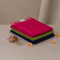 A stack of three folded fabric pieces in bright pink, olive green, and navy blue