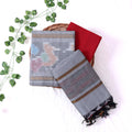 Top View Of Light Grey And Red Salwar Suit Material With Striped Dupatta, Ikkat Woven Border, Tassel Details & Fabric Piece