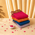 Kanchi cotton saree with bright pink body and contrast gold zari border neatly folded stack top view display.