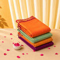 Kanchi cotton saree stack vibrant orange, green, yellow and purple shades with woven border, folded close up display 