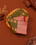 Two embroidered sarees in green and pink on a woven basket with a brown background