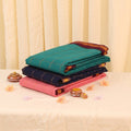 Sungudi cotton saree collection with gold check weave in teal, navy, and pink folded stack view