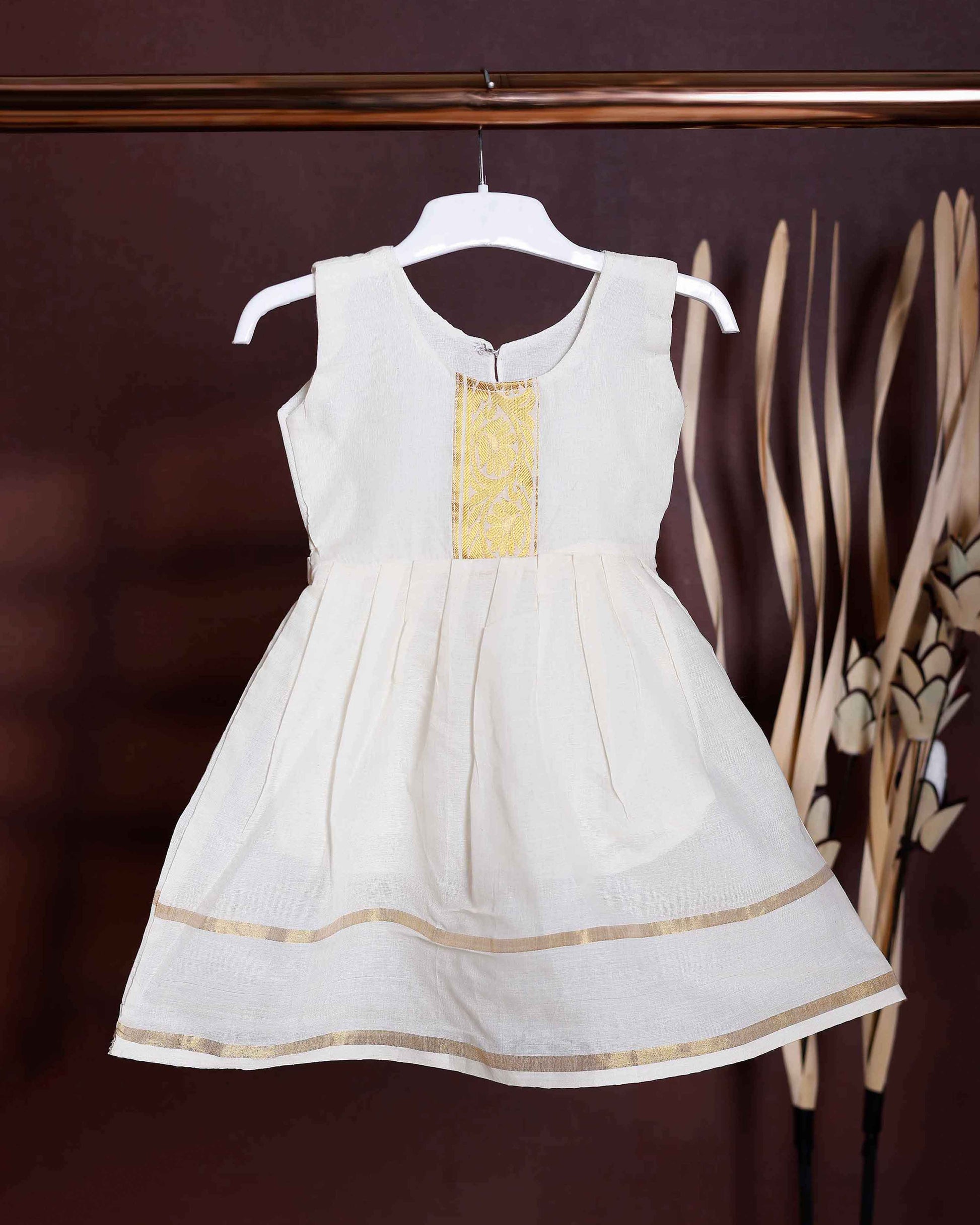 Traditional Kerala Kasavu Girls' Frock with Gold Zari Border & Embellished Neckline Traditional Kerala Kasavu Girls' Frock with Gold Zari Border & Embellished Neckline