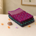 Art silk saree with intricate floral woven pattern in Purple and teal tones neatly folded stack close up product display view