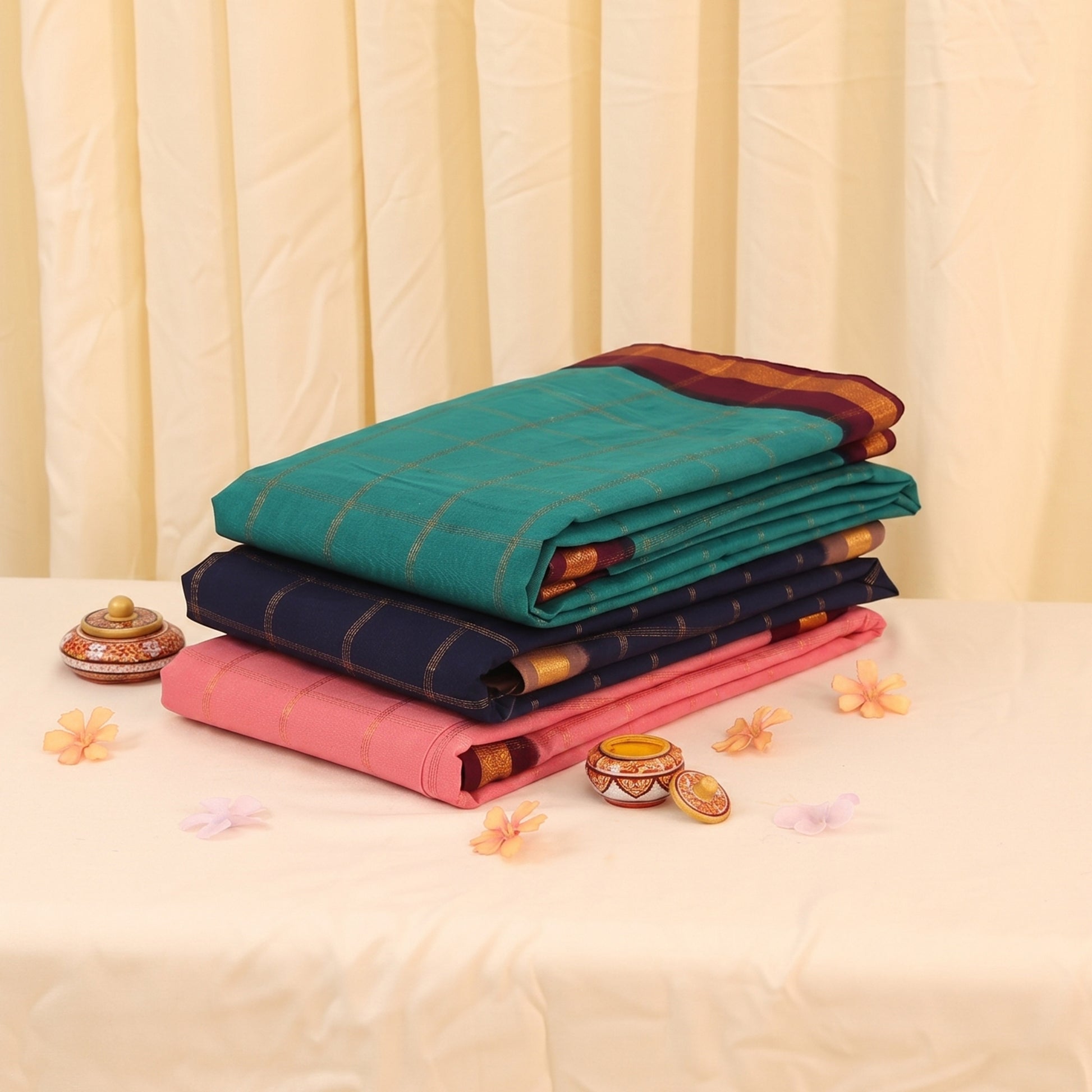 Sungudi cotton saree collection with gold check weave in teal, navy, and pink folded stack view