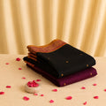 Kanchi cotton saree with black body and gold zari motifs maroon contrast border neatly folded stack front view with floral accents