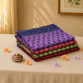 Voile cotton saree collection with floral motifs and printed borders in purple, pink, green and red folded stack display view
