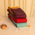 Elampillai silk cotton saree collection with contrast zari borders in stacked folded display close up view.