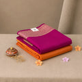 A stack of folded saree magenta and orange colors with gold zari embroidery