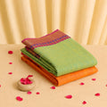 Kanchi cotton saree with temple motif zari border in pastel green and orange, folded front view