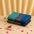 Kanchi cotton saree with turquoise blue body and contrast royal blue zari border, neatly folded in a stacked top view