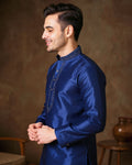 Man wearing a blue traditional outfit against a brown background