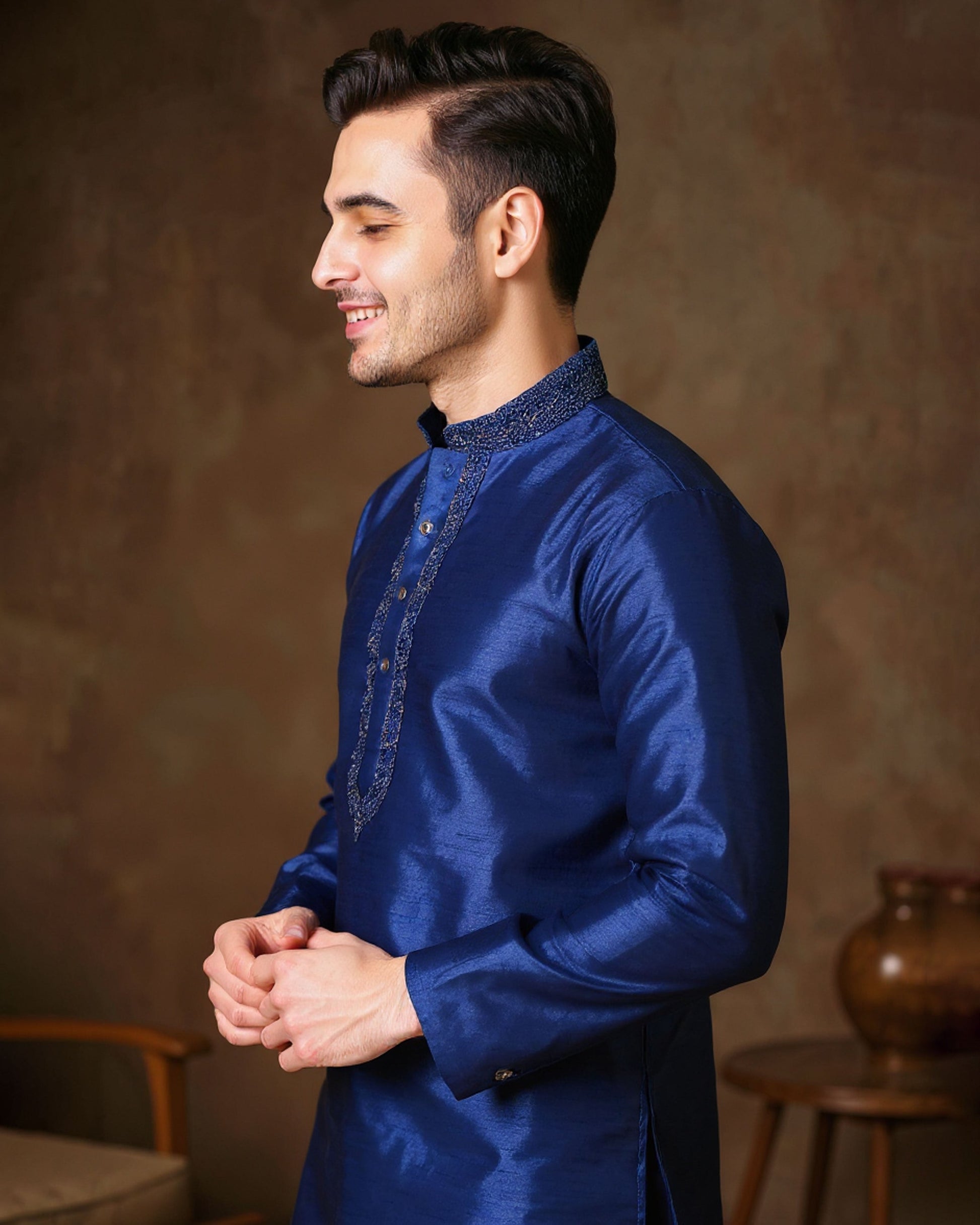 Man wearing a blue traditional outfit against a brown background