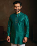 Man wearing a green kurta with embroidery against a dark background