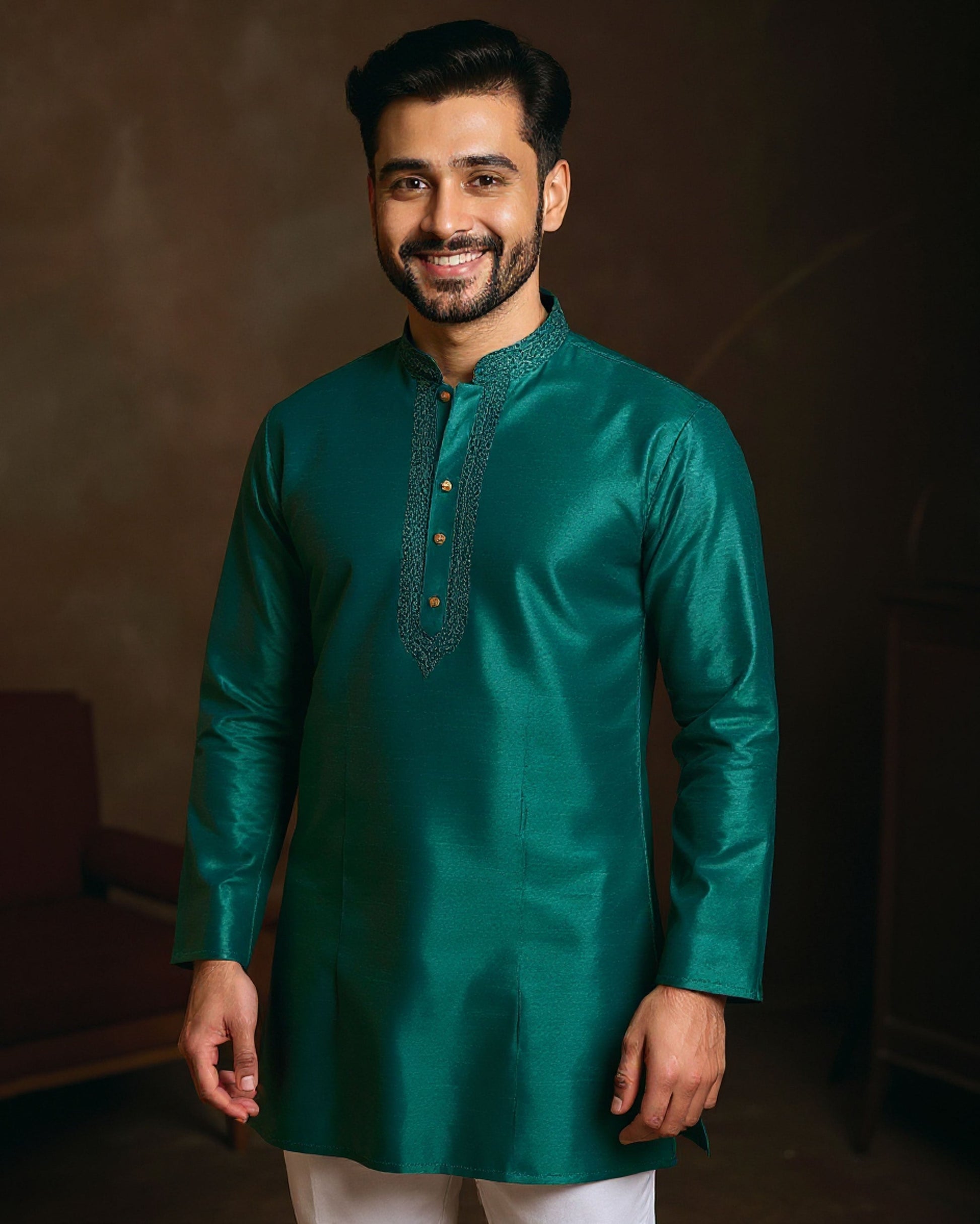 Man wearing a green kurta with embroidery against a dark background