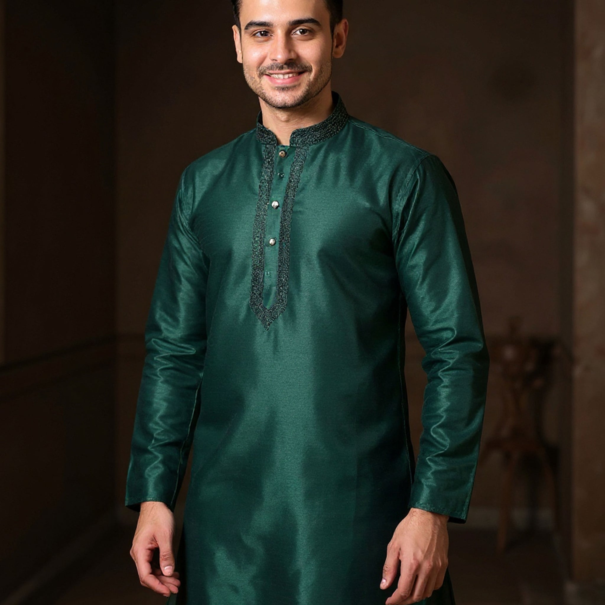 Man wearing a green kurta with white pants against a dark background