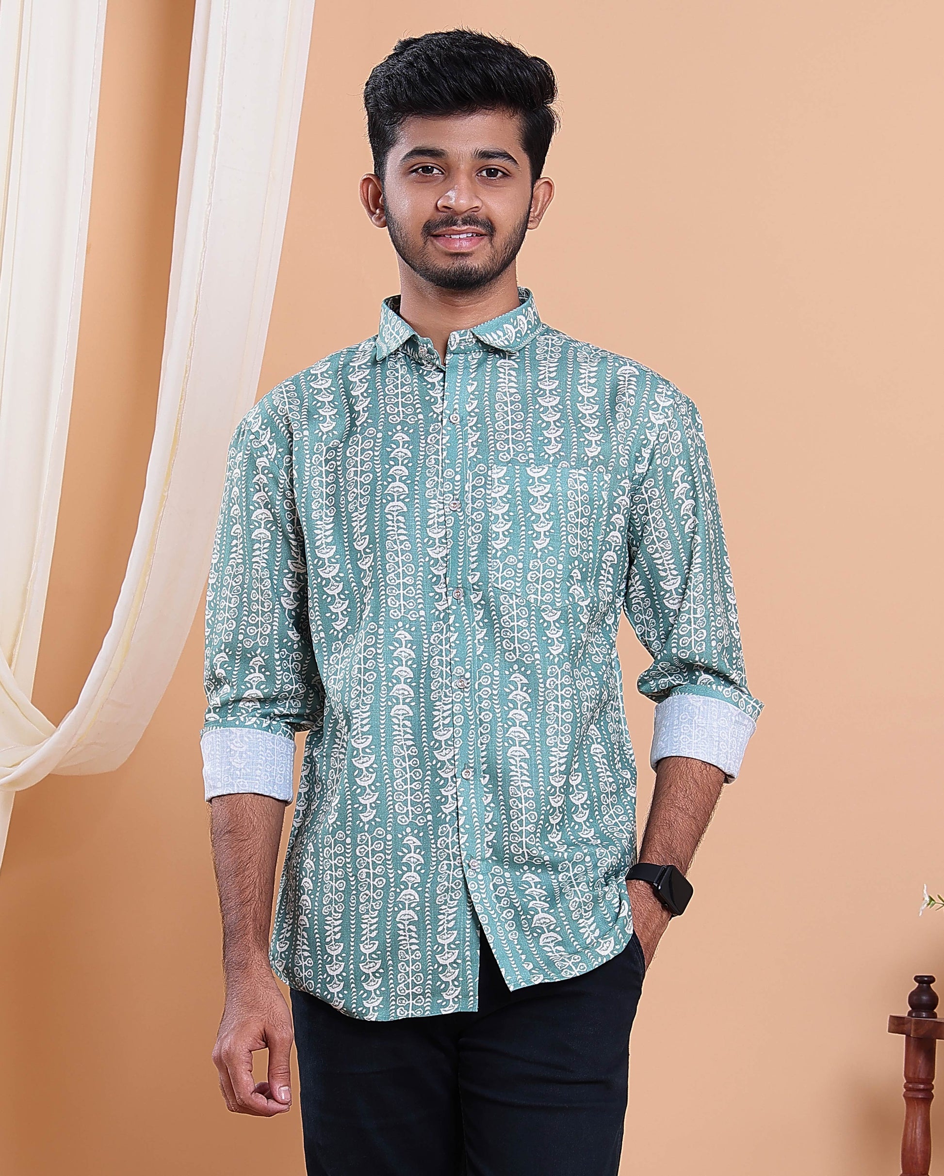 Man wearing a green patterned shirt against a beige background