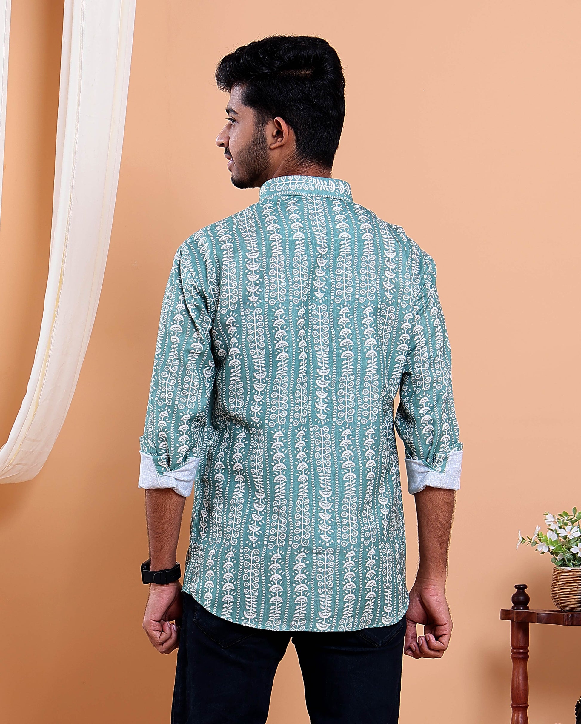 Man wearing a green patterned shirt against an orange background