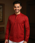 Man wearing a red kurta with white pants indoors
