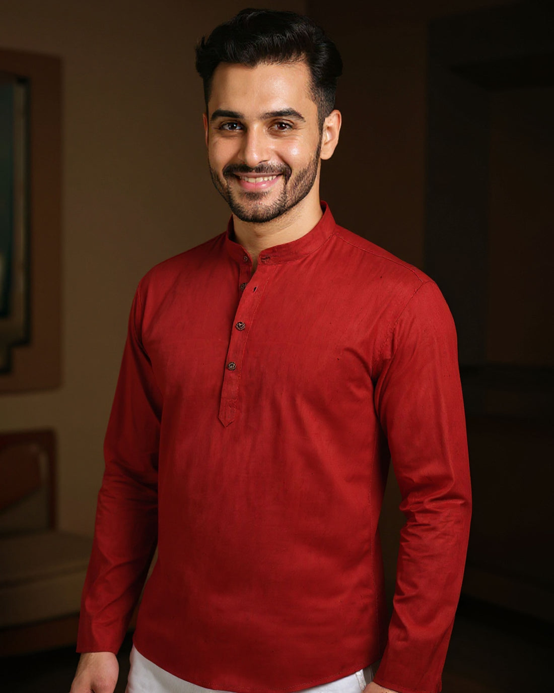 Man wearing a red kurta with white pants indoors