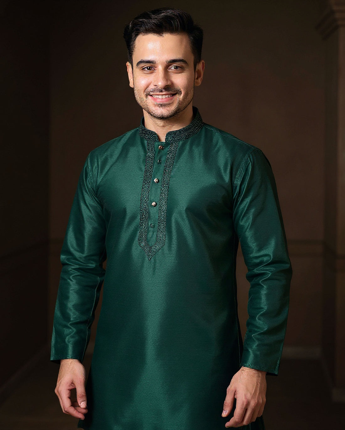 Man wearing a green kurta with white pants against a dark background