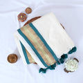Mul Mul cotton saree with cream body teal and gold zari border folded flat lay view with tassels and decorative accents