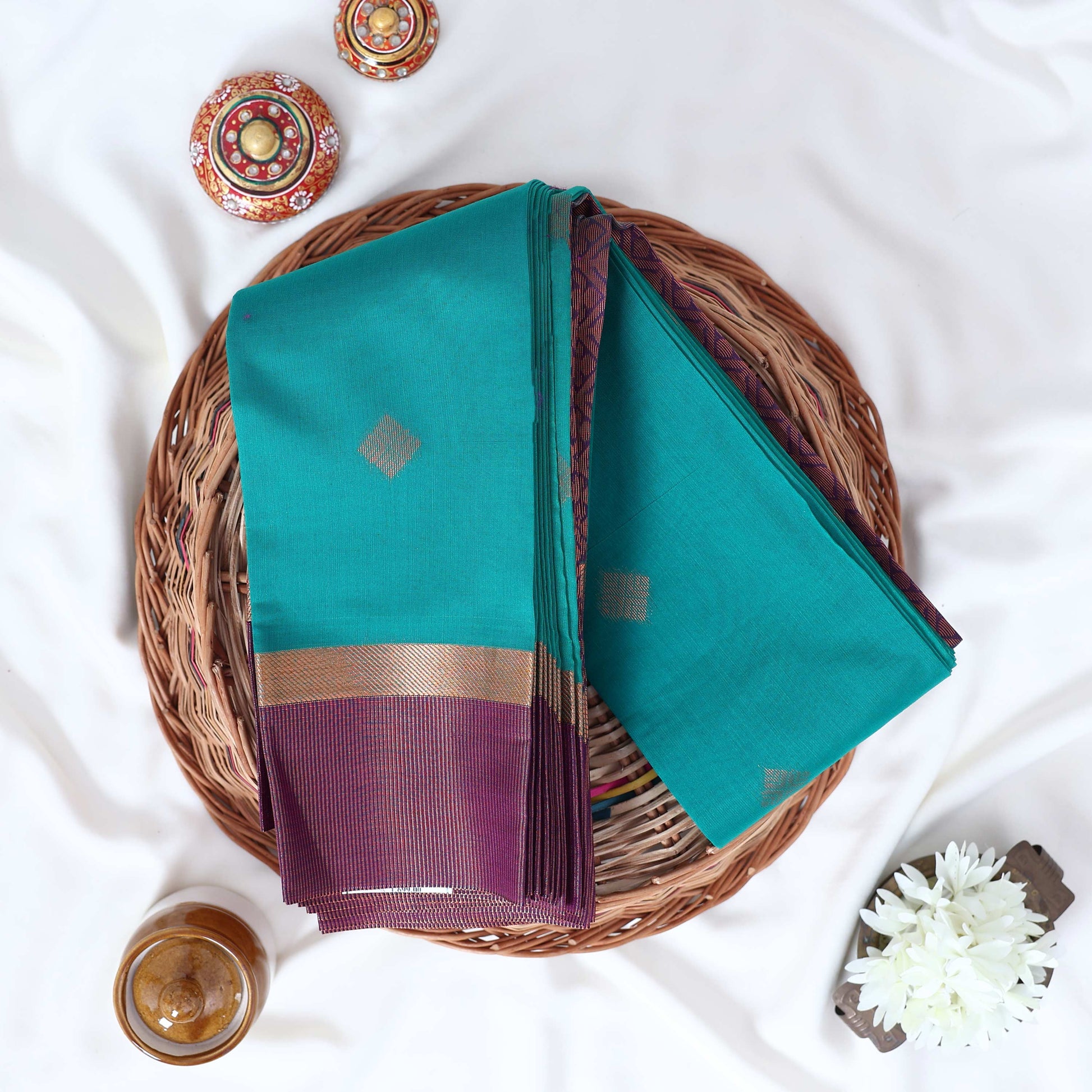 Dark Green Elampillai silk cotton saree with gold zari buttas and contrast zari border, folded top view.