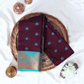 Purple Elampillai silk cotton saree with woven butta motifs and floral zari contrast border folded top view display.