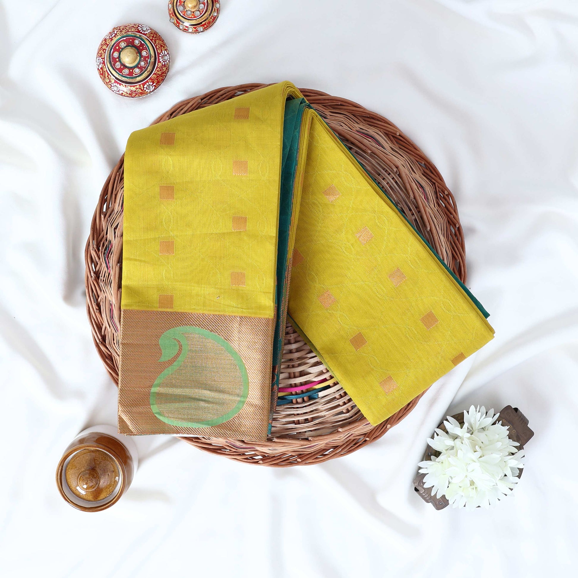 Green Elampillai silk cotton saree with gold zari buttas and contrast paisley zari border folded top view