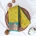 Green Elampillai silk cotton saree with woven butta motifs and floral zari contrast border folded top view display.