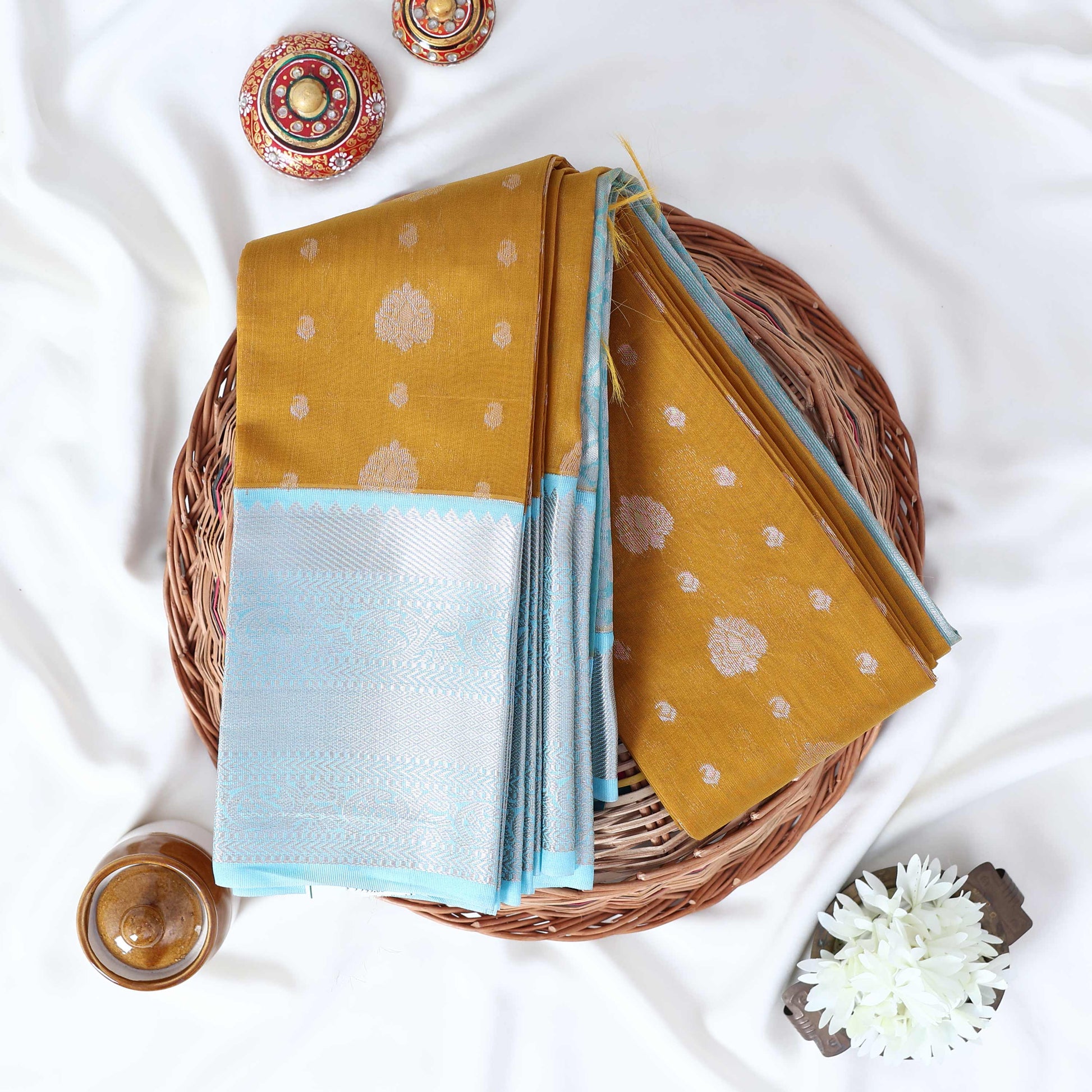 Elampillai silk cotton saree with silver zari floral motifs and broad contrast zari border in light green top view