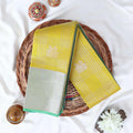 Elampillai silk cotton saree with floral butta checks pattern and floral zari border in green folded top view.