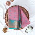 Pink Elampillai silk cotton saree with woven butta motifs and floral zari contrast border folded top view display.