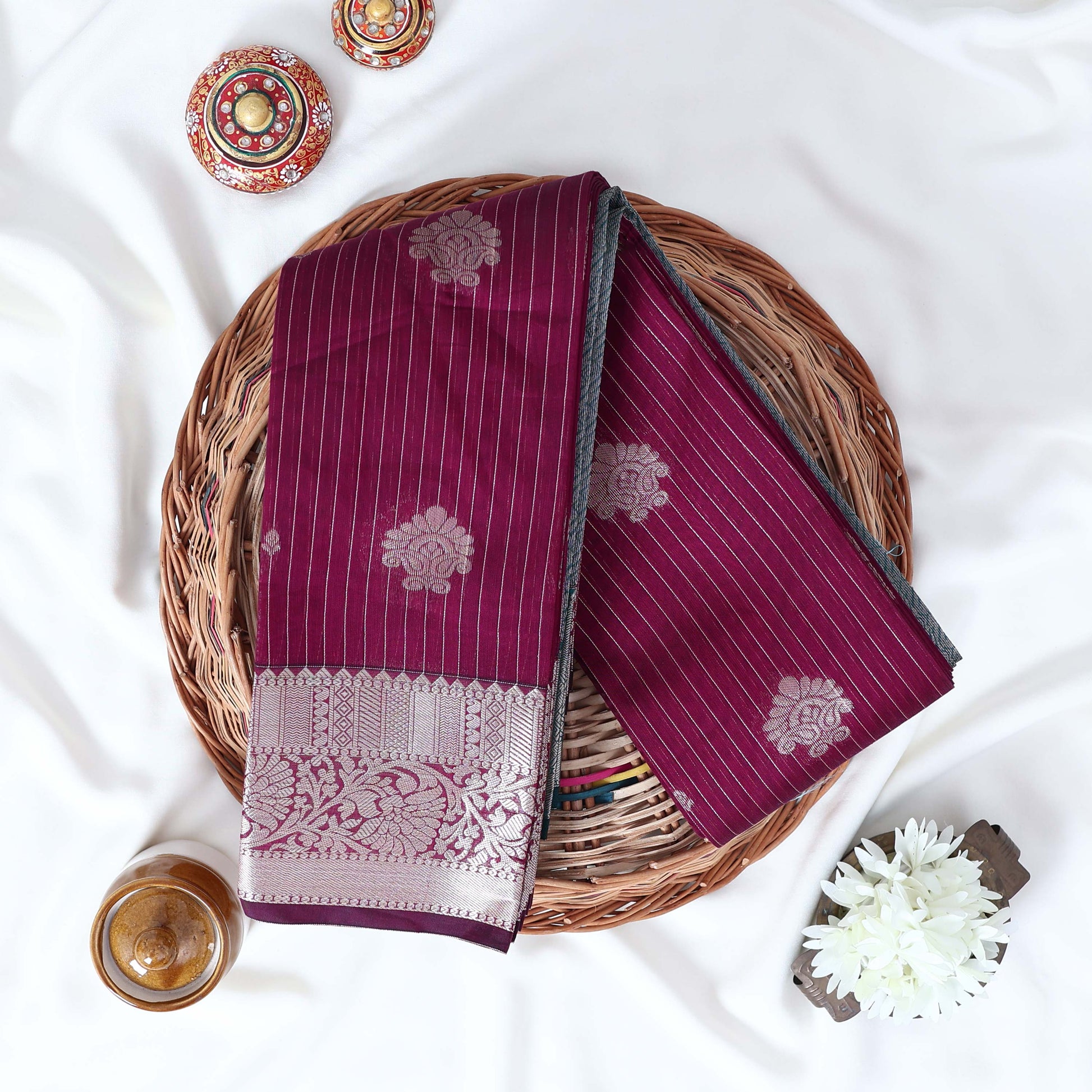 Purple Elampillai silk cotton saree with silver zari floral buttas, vertical stripes and contrast floral zari border folded top view