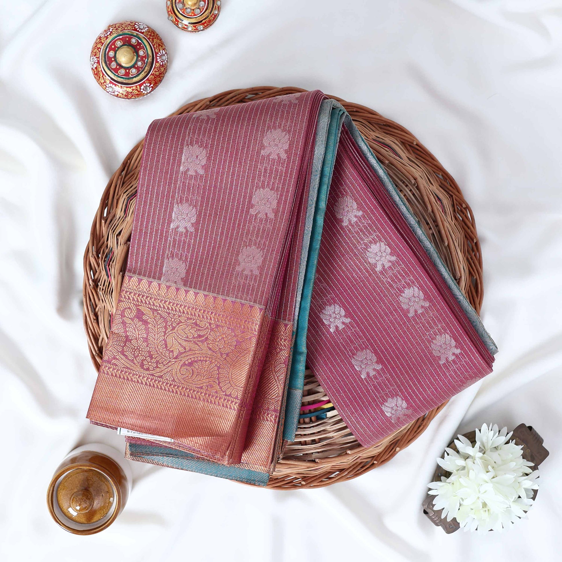 Purple Elampillai silk cotton saree with silver floral zari buttas, vertical stripes and contrast zari border folded top view