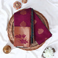 Elampillai silk cotton saree with floral zari border in purple folded display on wicker basket top view.