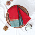 Red Elampillai silk cotton saree with gold zari buttas and contrast zari border, folded top view.