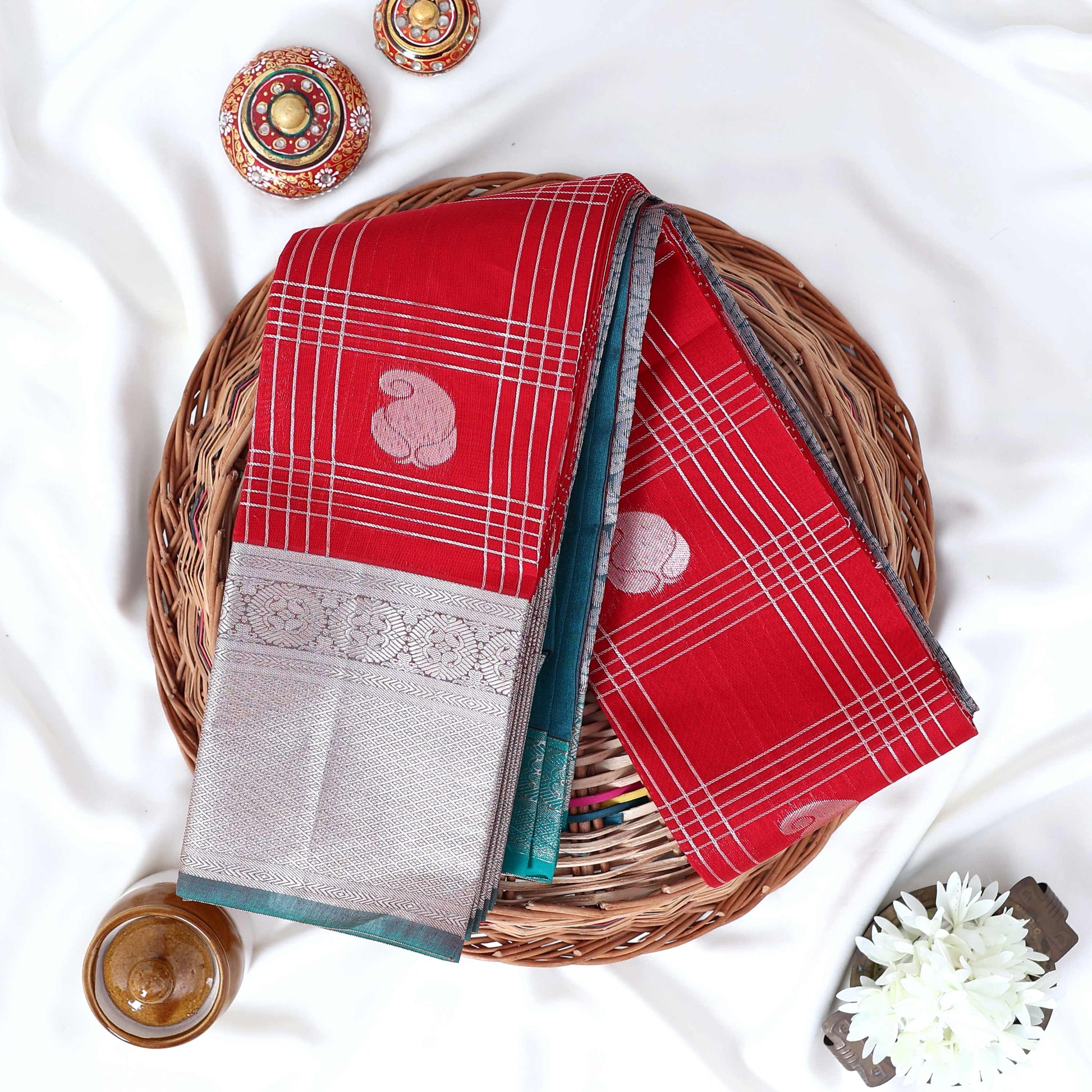 Elampillai silk cotton saree with floral butta checks pattern and floral zari border in red top view display.