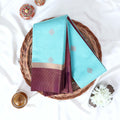 Sky blue Elampillai silk cotton saree with gold zari buttas and contrast zari border folded top view.