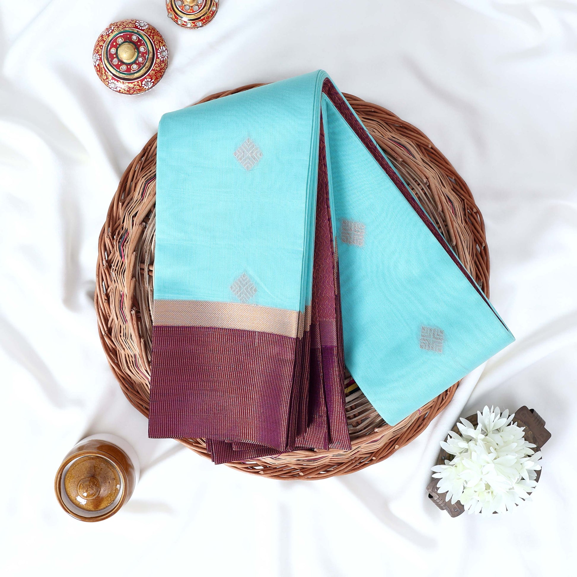 Sky blue Elampillai silk cotton saree with gold zari buttas and contrast zari border folded top view.